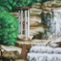 Clopoței de vânt din metal, agățați în fața unei mici cascade